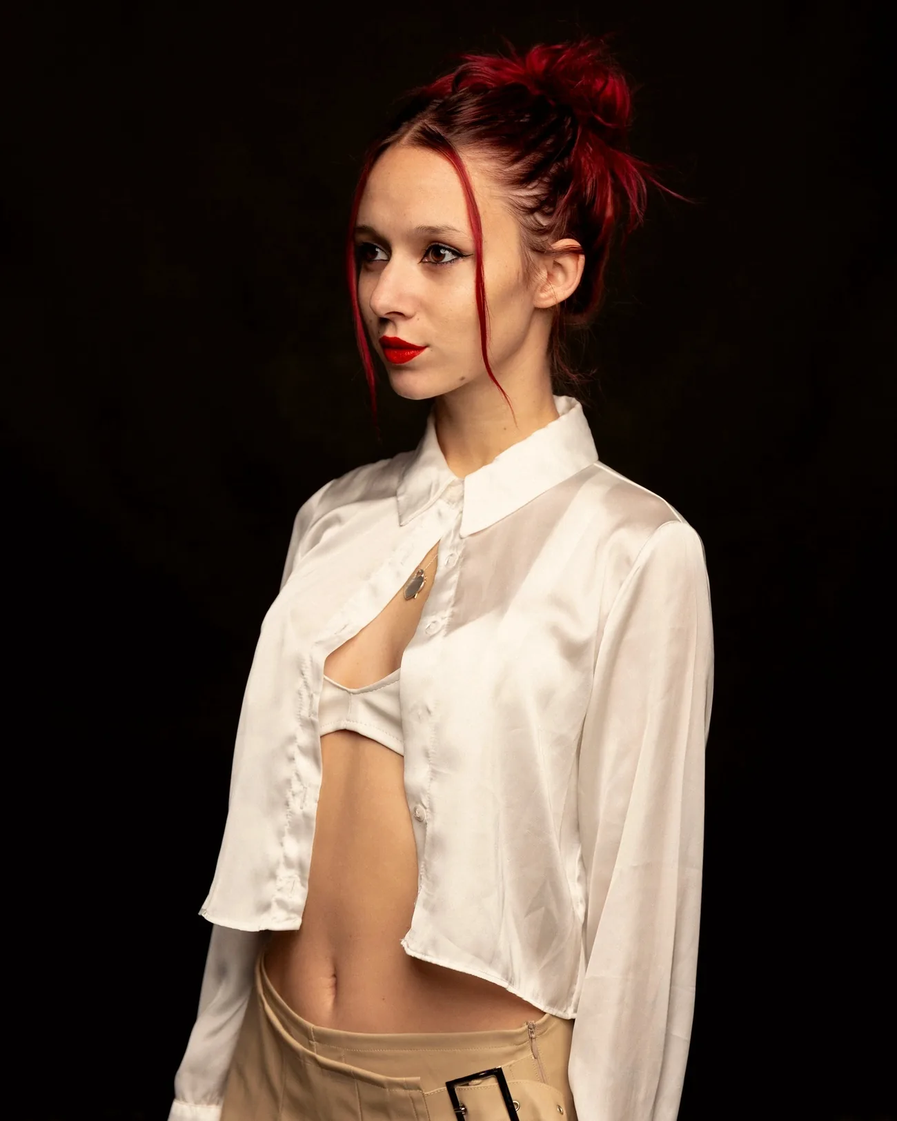 Retrato de estudio de Luana Digier sobre fondo negro, camisa de satén blanco y labios rojos
